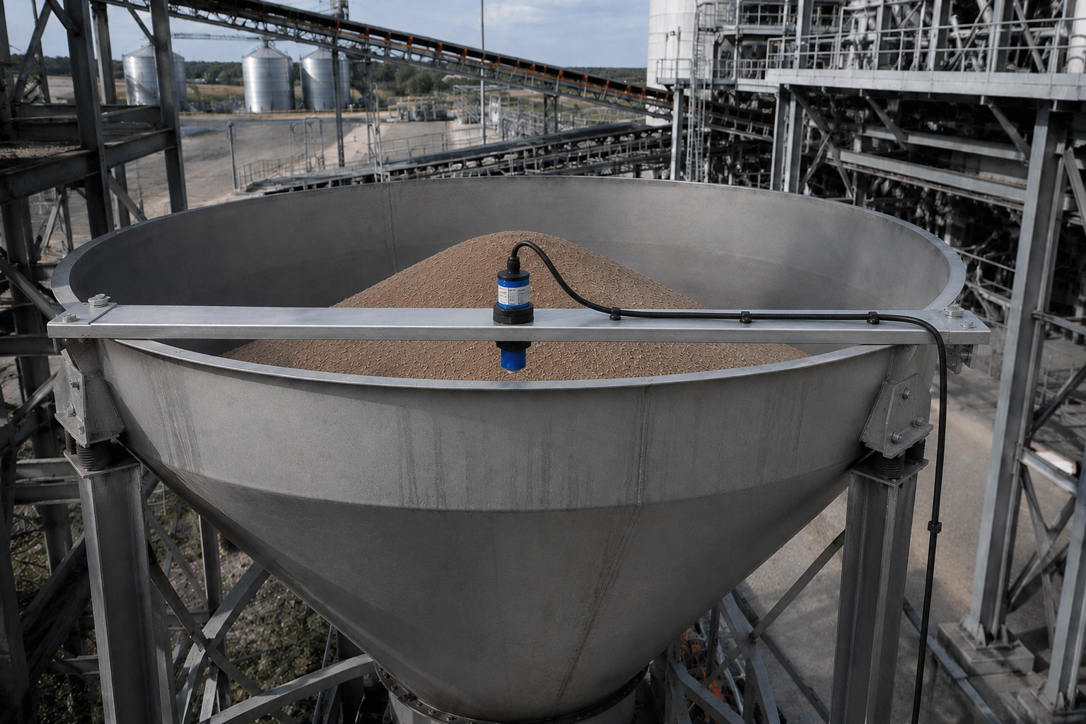 Ultrasonic level sensor mounted at top of large industrial bin or hopper measuring material fill level